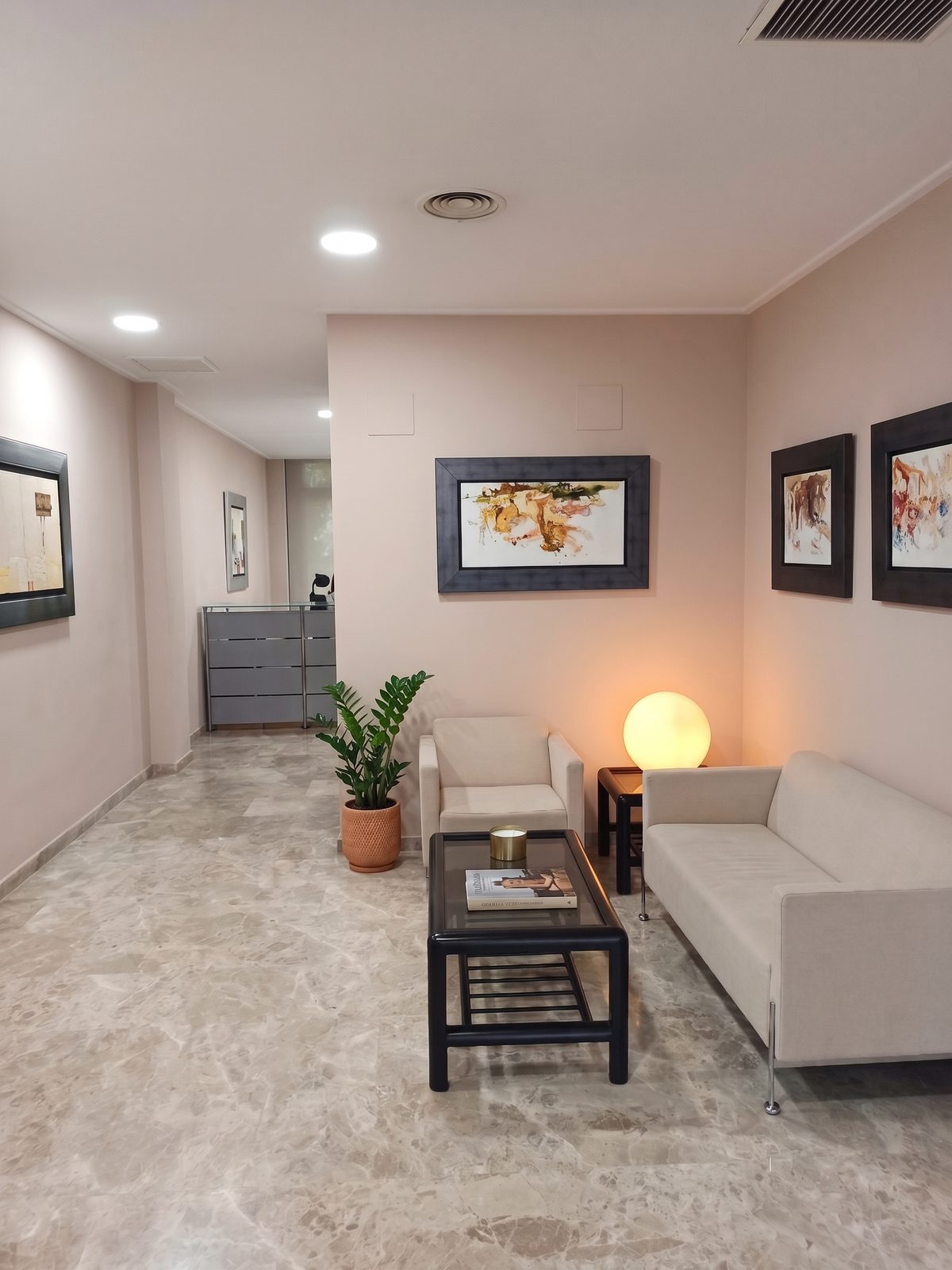 Sala de espera de Gabinete Mompó S.L., con sofás y cuadros